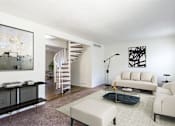 Thumbnail 43 of 43 - A living room with a white couch, a black coffee table, and a spiral staircase at Spring Creek Townhomes Apartments, Springfield 62702