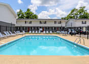 Thumbnail 2 of 43 - A large swimming pool in front of a building with lounge chairs around it at Spring Creek Townhomes Apartments, Springfield, IL