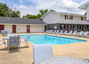 Thumbnail 23 of 43 - A pool with chairs around it and a building in the background at Spring Creek Townhomes Apartments, Springfield