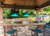 Thumbnail 18 of 42 - A patio with a bar and chairs under a roof.