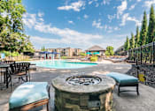 Thumbnail 15 of 42 - A pool area with a fountain in the middle and chairs around it.