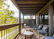 Thumbnail 37 of 42 - A wooden balcony with chairs and tables.