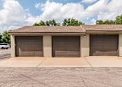 Thumbnail 40 of 42 - A building with three garage doors is in front of a tree.