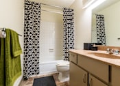 Thumbnail 32 of 42 - A bathroom with a toilet, sink, and shower curtain.