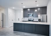 Thumbnail 71 of 73 - A modern kitchen with a white countertop and dark grey cabinets. at The MK, Indiana