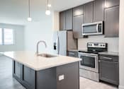 Thumbnail 61 of 73 - A modern kitchen with dark grey cabinets and stainless steel appliances. at The MK, Indianapolis, IN