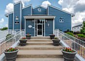 Thumbnail 50 of 50 - A blue building with a white fence and flower pots in front.