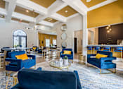 Thumbnail 25 of 40 - A large room with blue chairs and a gold coffee table at Waterstone at Cinco Ranch Apartments, Katy, TX