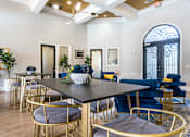 Thumbnail 27 of 40 - A dining room with a black table surrounded by blue chairs at Waterstone at Cinco Ranch Apartments, Katy Texas