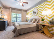 Thumbnail 11 of 40 - A bedroom with a bed, nightstand, and a ceiling fan at Waterstone at Cinco Ranch Apartments, Texas