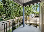 Thumbnail 49 of 59 - A balcony with a black railing and a view of a backyard.