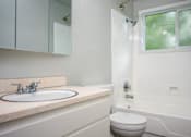 Thumbnail 9 of 22 - A white bathroom with a toilet, sink, and bathtub.