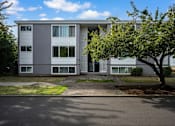 Thumbnail 2 of 22 - A tree is in front of a grey building.