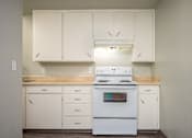 Thumbnail 6 of 22 - A white stove in a kitchen with white cabinets.
