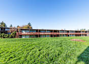 Thumbnail 15 of 26 - A long building with a lot of windows sits on a grassy field.