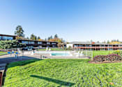 Thumbnail 13 of 26 - A large grassy area in front of a building with a pool.