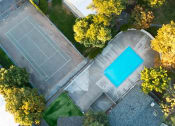 Thumbnail 13 of 16 - arial view of a tennis court and a pool in a backyard with trees