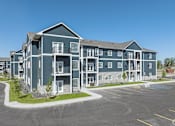 Thumbnail 20 of 46 - an apartment building with a parking lot and a street