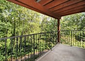 Thumbnail 4 of 24 - A balcony with a metal railing and a view of a wooded area.