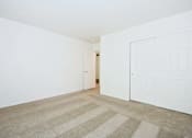 Thumbnail 15 of 24 - A room with a striped carpet and two white doors.