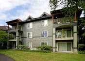 Thumbnail 3 of 24 - A grey two story apartment building with balconies.