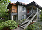 Thumbnail 1 of 24 - A grey house with a red door and a staircase leading to the second floor.