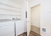 Thumbnail 19 of 24 - A white washing machine and dryer in a small laundry room.