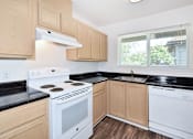 Thumbnail 9 of 24 - A kitchen with wooden cabinets and black countertops.