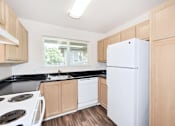 Thumbnail 8 of 24 - A kitchen with a white refrigerator, black countertops, and wooden cabinets.