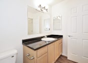 Thumbnail 13 of 24 - A bathroom with a sink, mirror, and toilet.