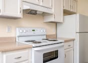 Thumbnail 49 of 56 - A white stove top oven with a white refrigerator in a kitchen.