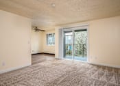 Thumbnail 52 of 56 - A spacious room with a ceiling fan and sliding glass doors leading to a balcony.