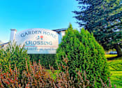 Thumbnail 5 of 26 - A sign for Garden Home Crossing stands in front of a green hedge.