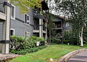 Thumbnail 2 of 24 - Apartment building with a stone wall and green grass.