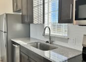 Thumbnail 25 of 46 - a kitchen with stainless steel appliances and a granite counter top