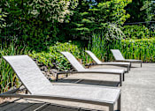 Thumbnail 6 of 30 - A set of four sun loungers are arranged in a row on a concrete surface.