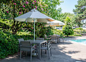 Thumbnail 8 of 30 - A patio with a table and chairs under an umbrella.