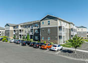 Thumbnail 14 of 48 - an apartment building with cars parked in a parking lot