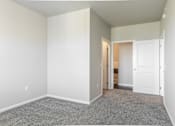 Thumbnail 8 of 48 - an empty room with carpet and a door to a bathroom