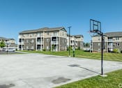 Thumbnail 11 of 48 - an empty basketball court with an apartment building in the background