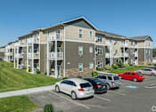 Thumbnail 13 of 48 - an apartment building with cars parked in a parking lot