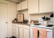 Thumbnail 22 of 26 - A kitchen with white cabinets and a white stove top oven.