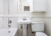 Thumbnail 20 of 52 - A white bathroom with a tub, toilet, and sink.