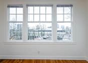 Thumbnail 18 of 52 - A room with a large window overlooking a parking lot and buildings.