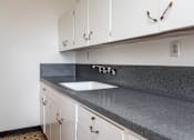 Thumbnail 9 of 52 - A kitchen with white cabinets and a grey countertop.