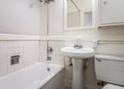 Thumbnail 21 of 52 - A white bathroom with a tub, sink, and mirror.