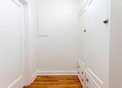 Thumbnail 16 of 52 - A white hallway with a wooden floor and white walls.