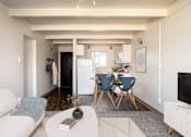 Thumbnail 2 of 26 - A living room with a white sofa, a grey rug, a white coffee table, a blue chair and a white cabinet.