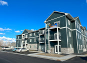 Thumbnail 36 of 46 - a green apartment building with cars parked outside