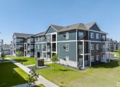 Thumbnail 21 of 46 - an image of an apartment building with green grass and a sidewalk